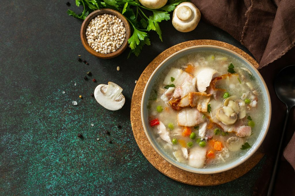 Healthy eating. Homemade hearty soup with cereals, bacon and mushrooms on a dark stone background.